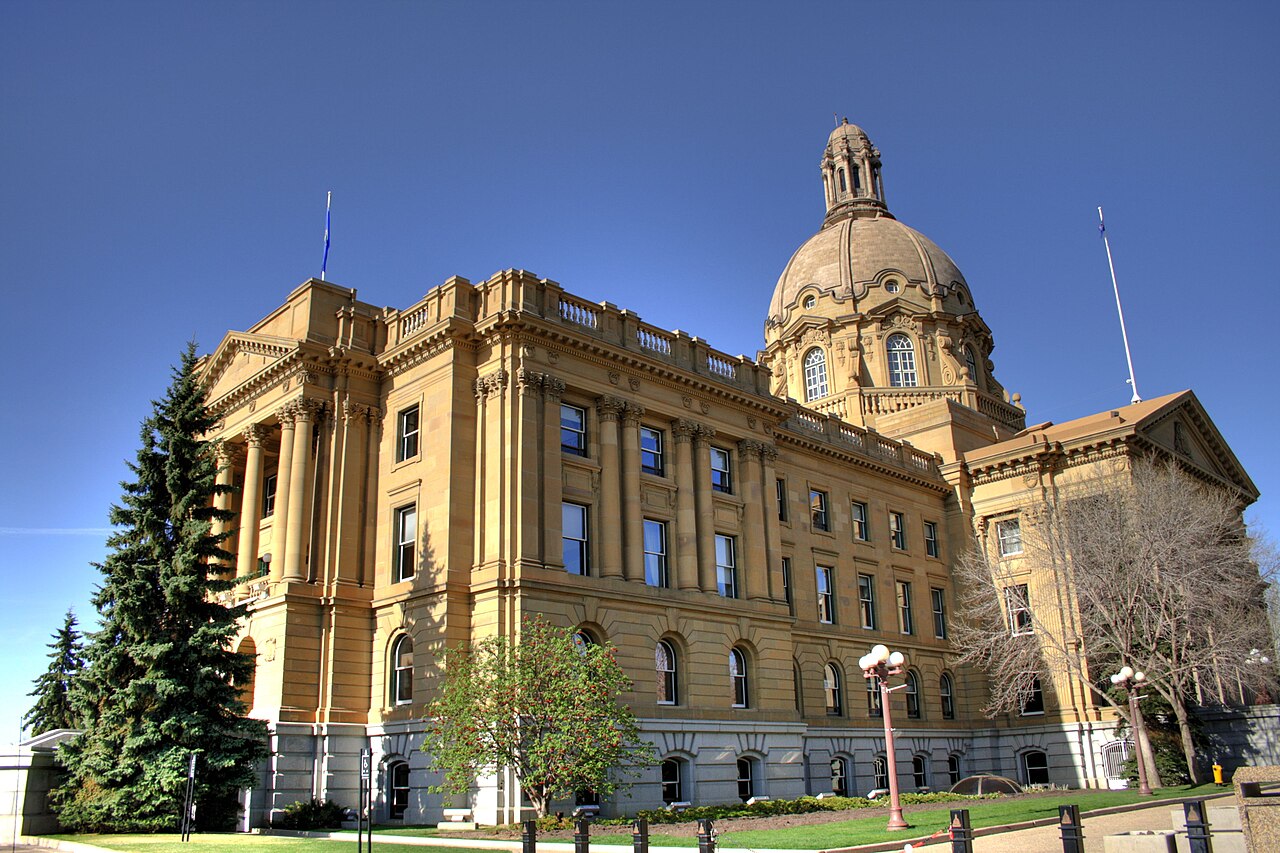 Alberta Legislature Building in Edmonton, with a central dome and columned stone facade under a clear blue sky.