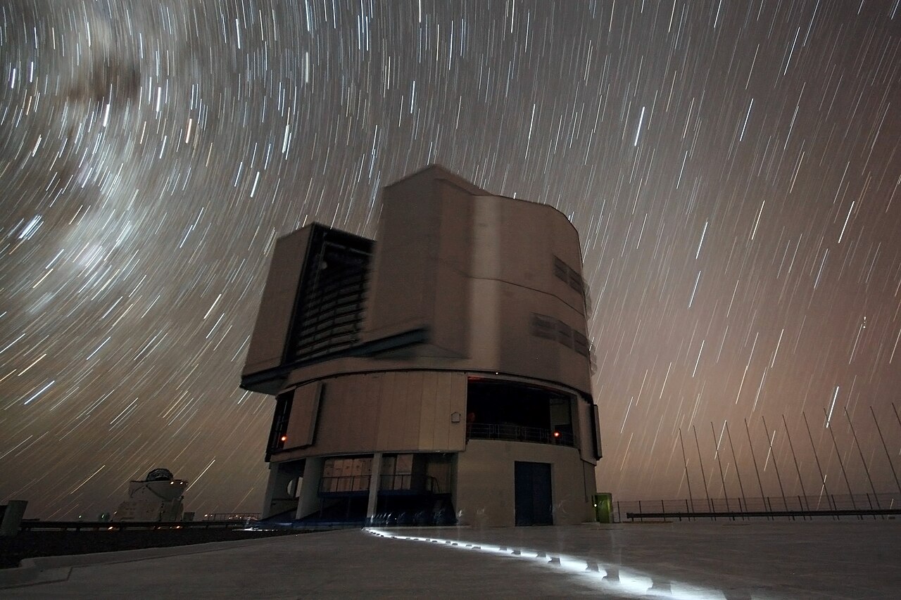 Long-exposure star trails curve above an enclosure of ESO’s Very Large Telescope at Paranal Observatory.