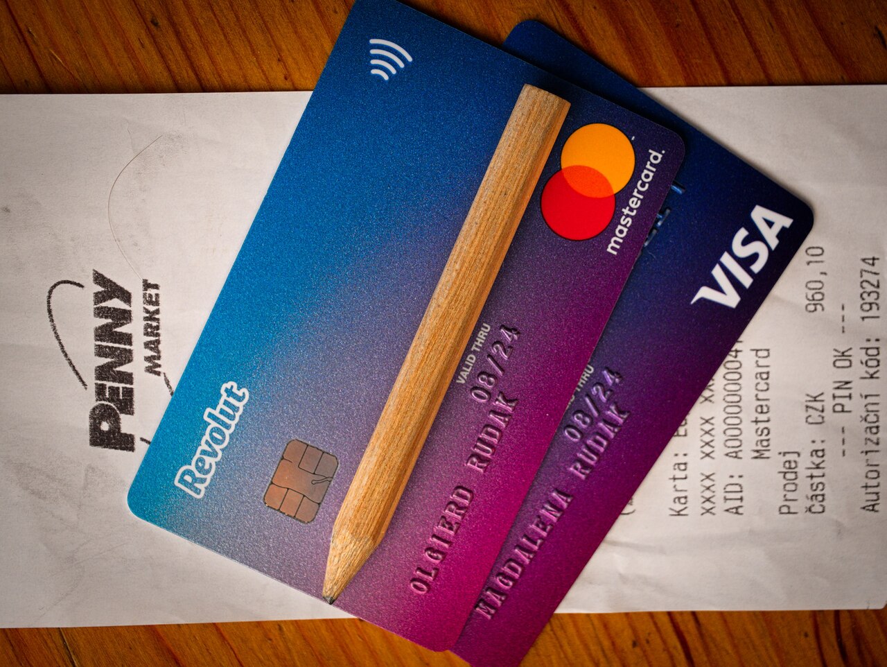 Two overlapping Revolut payment cards on a receipt, with a pencil across them.