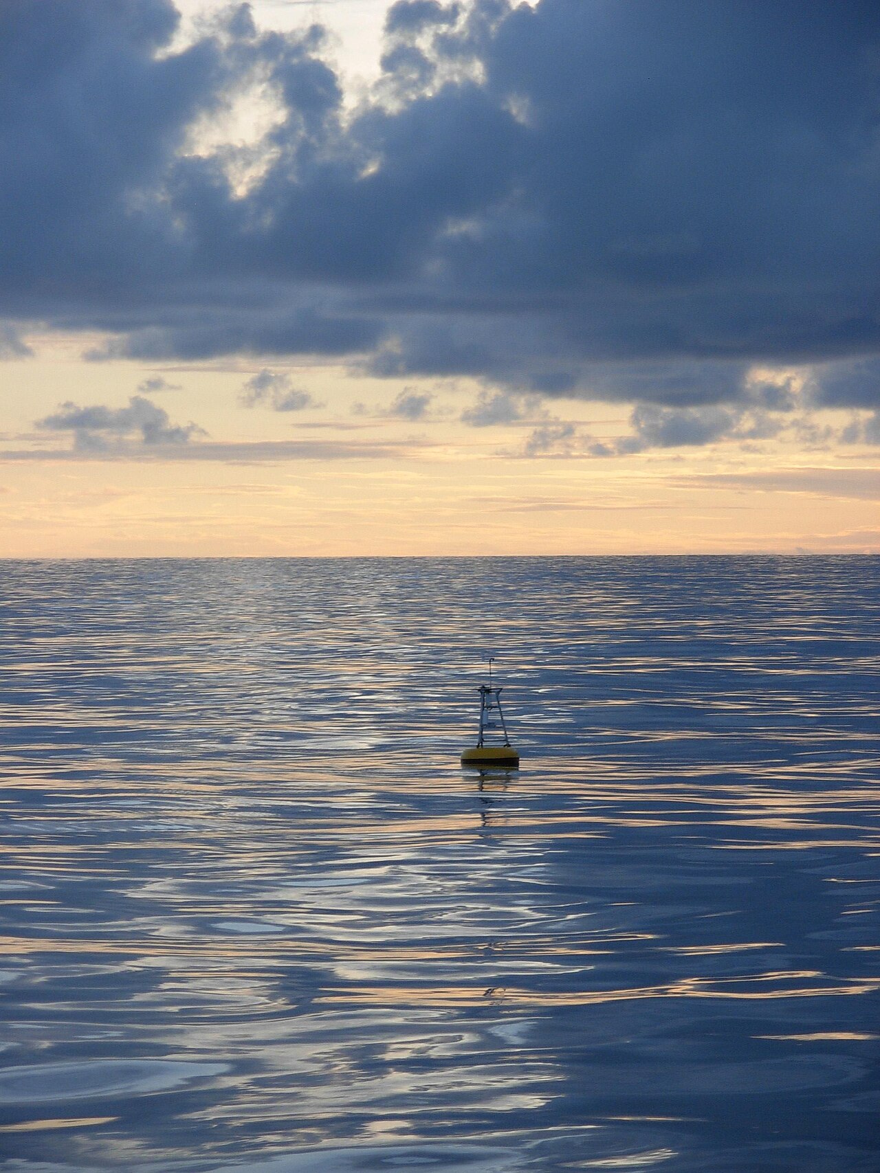 A yellow NOAA ocean-monitoring buoy floating beneath clouds in the equatorial Pacific.