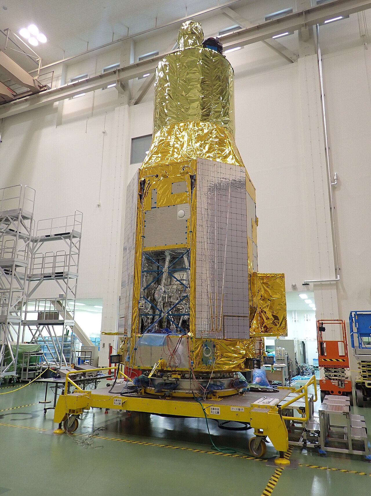 Gold-foil-wrapped XRISM spacecraft standing vertically inside a cleanroom at Japan’s Tsukuba Space Center.
