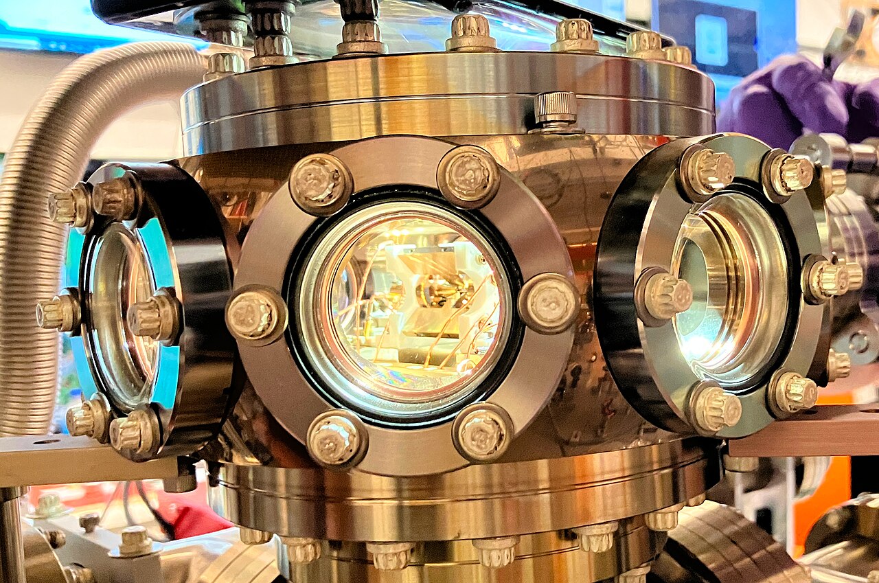 Close view of a stainless-steel linear Paul ion trap vacuum chamber with several circular laser-access windows.