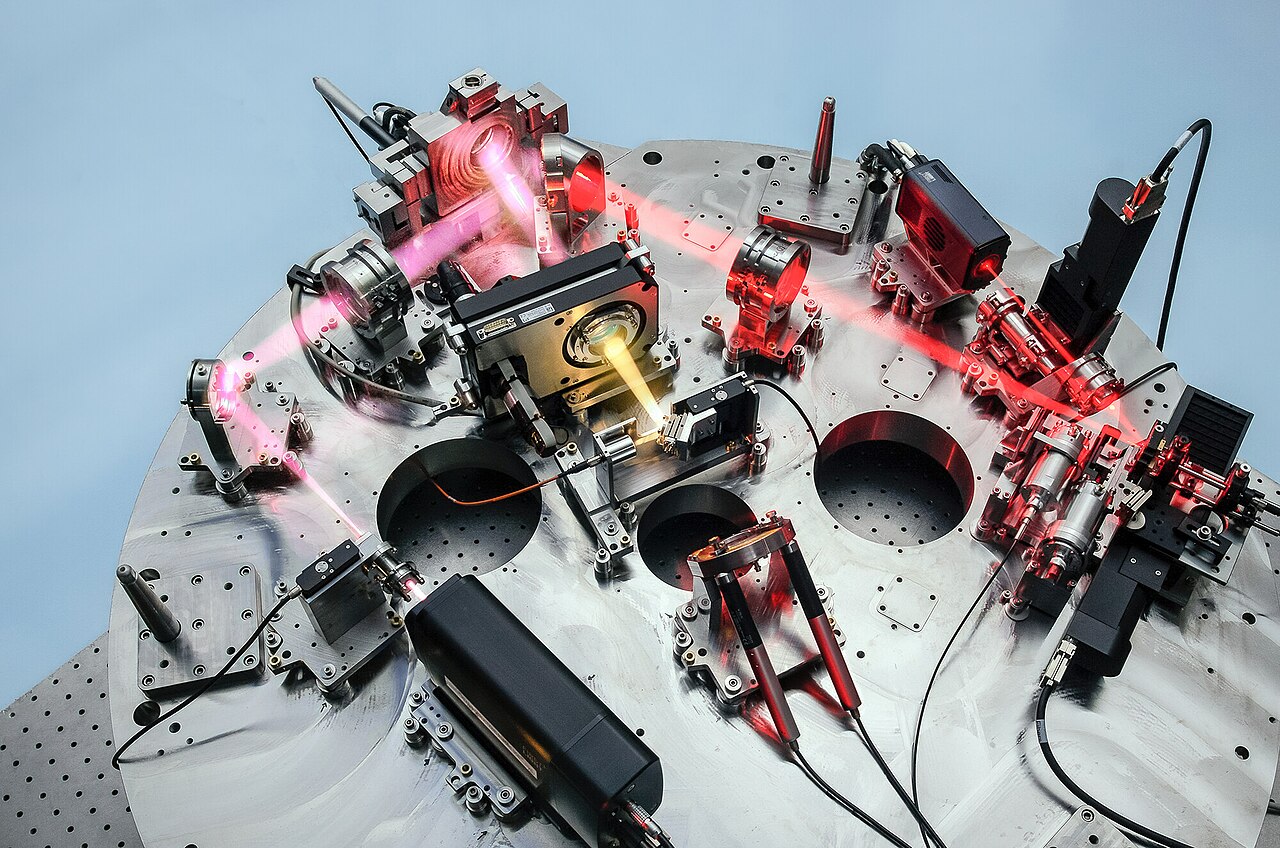 NIRPS adaptive-optics assembly with mirrors, lenses and red laser beams mounted on a circular optical bench.