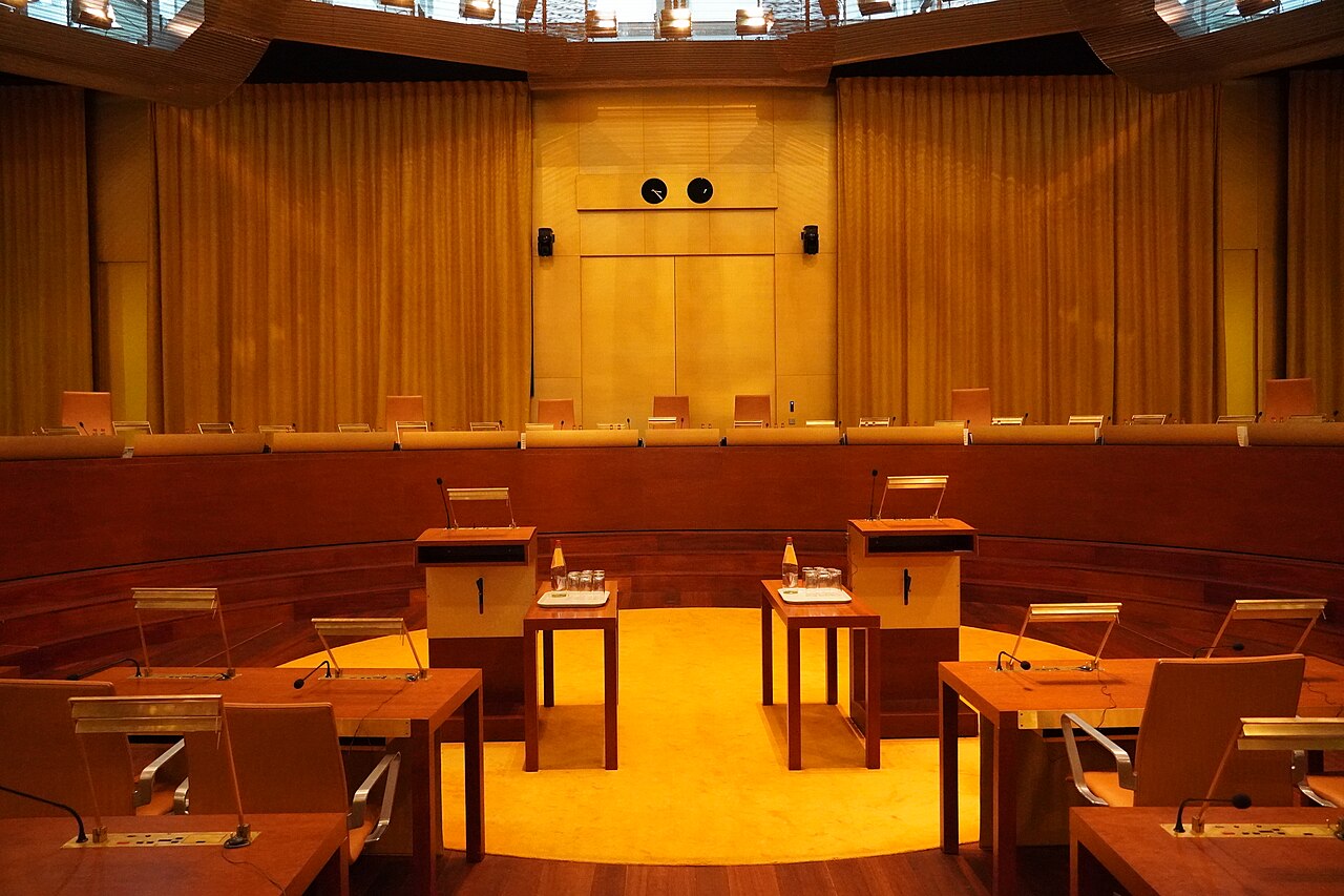 Empty main courtroom of the Court of Justice of the European Union in Luxembourg, with judges’ bench and counsel tables.