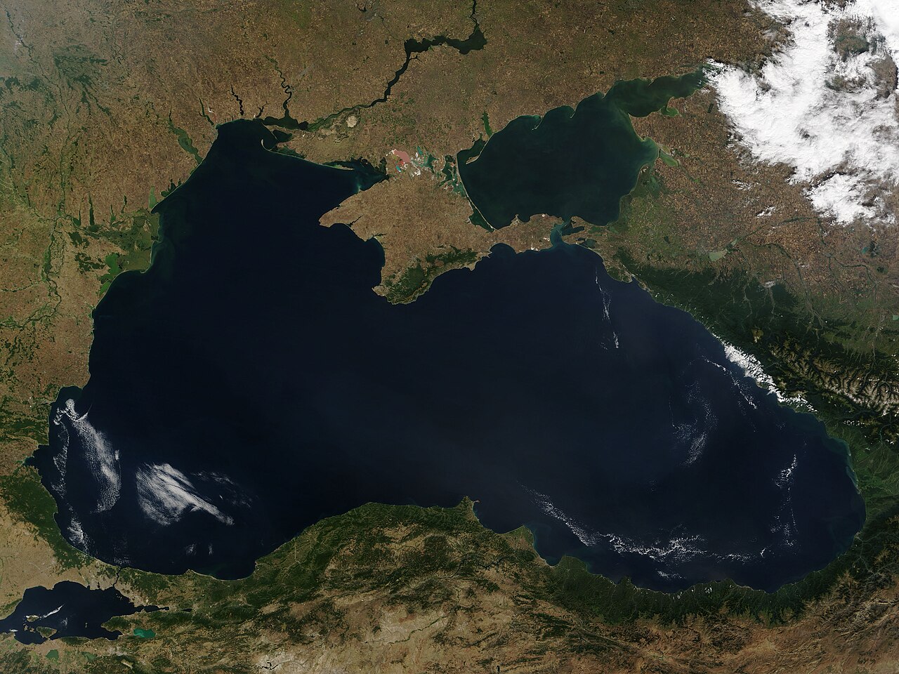 Satellite view of the Black Sea, Crimea and the Sea of Azov, surrounded by land and scattered clouds.